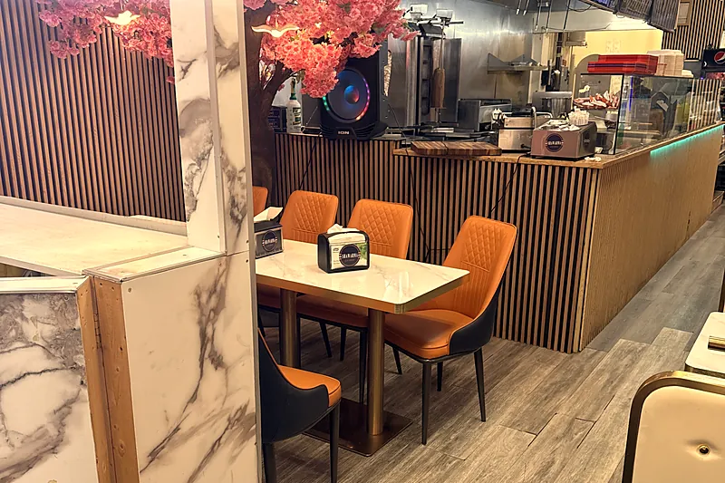 Dining room on 17th Ave with orange chairs, a blossom tree and the shawarma counter