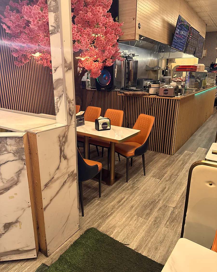Dining room on 17th Ave with orange chairs, a blossom tree and the shawarma counter