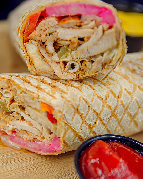 Chicken shawarma wrap cut in half, with pickled turnip