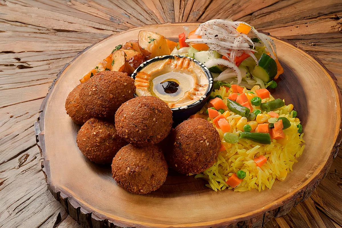 Falafel platter on a wooden board with hummus, rice and salad