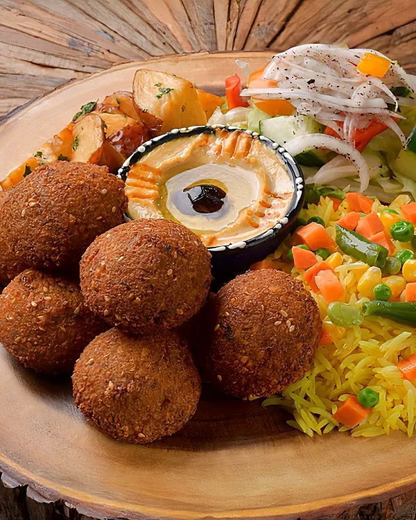 Falafel platter on a wooden board with hummus, rice and salad