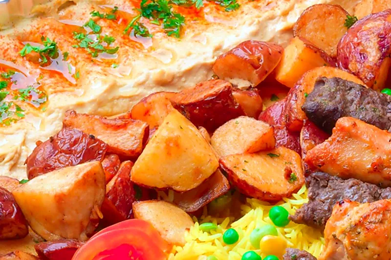 Garlic potatoes next to hummus in a family tray
