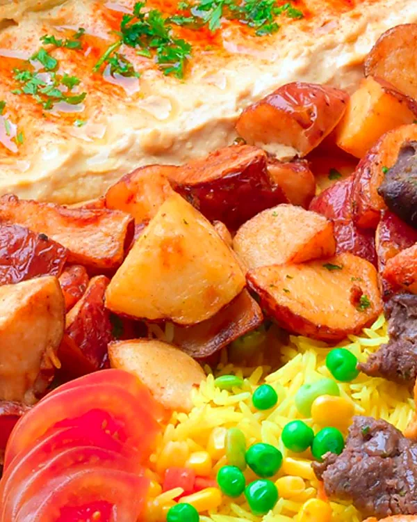 Garlic potatoes next to hummus in a family tray