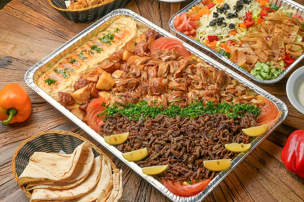 Shawarma platter tray with chicken and beef shawarma, hummus and garlic potatoes, with pita and a salad tray