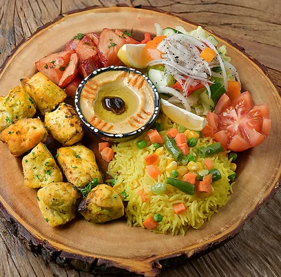 Shish tawook chicken with rice, hummus and salad on a wooden board
